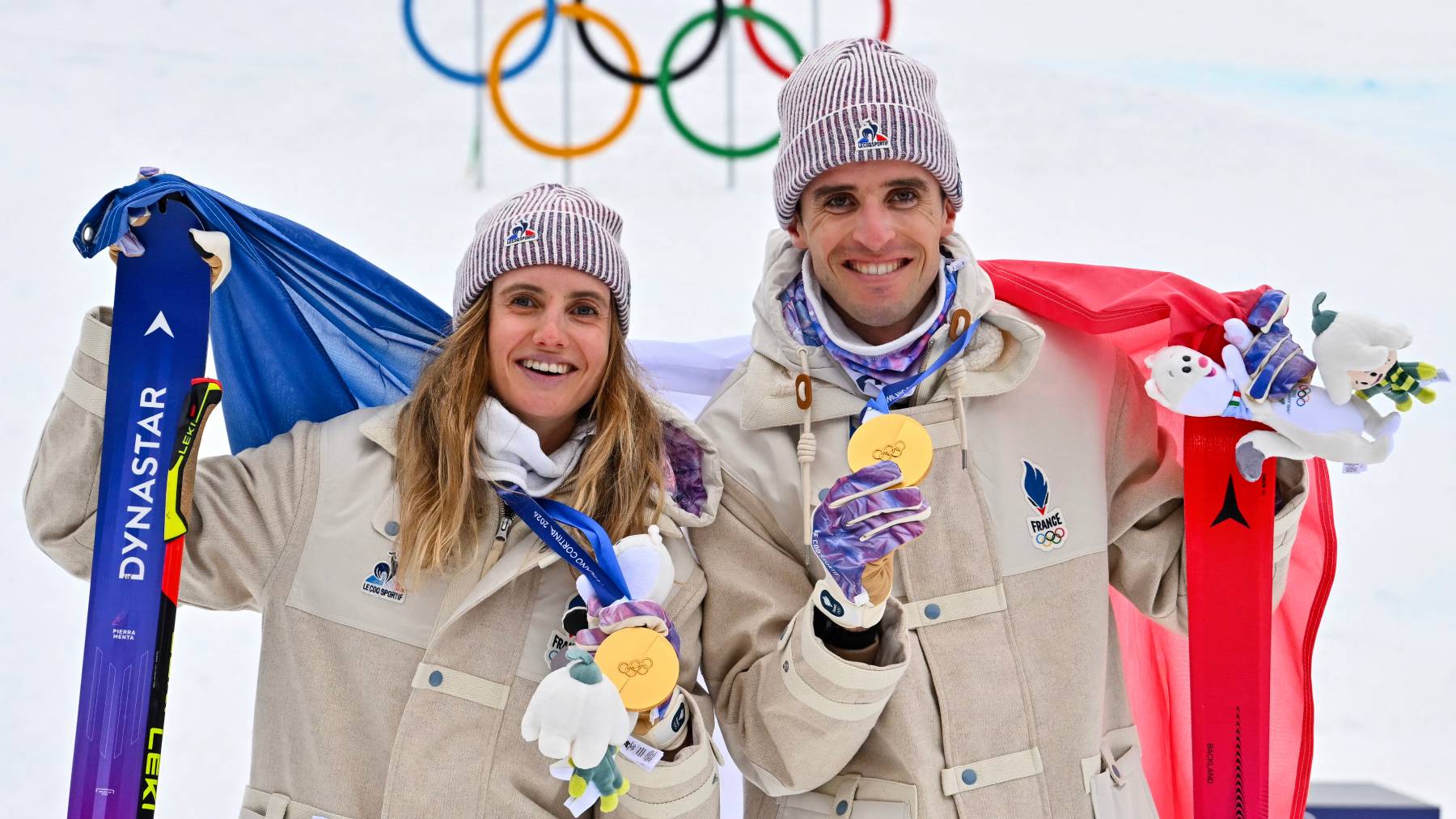 Gold medallists France's Thibault Anselmet (R) and France's Emily Harrop celebrate on the podium after competing in the mixed relay ski mountaineering event during the Milano Cortina 2026 Winter Olympic Games at the Stelvio Ski Centre in Bormio (Valtellina) on February 21, 2026.